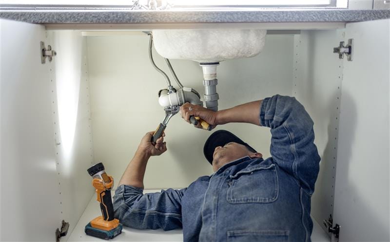 Plumber repairing pipes beneath a bathroom sink in Tampa