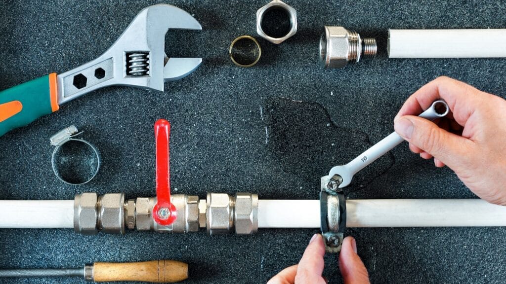 Plumber repairing a pipe valve with an adjustable wrench in Tampa