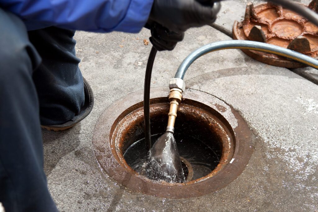 Plumber hydro jetting a sewer line through a manhole in Tampa