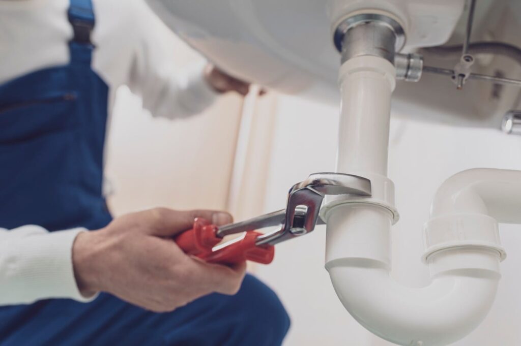 Plumber repairing a white drain pipe beneath a sink in Tampa
