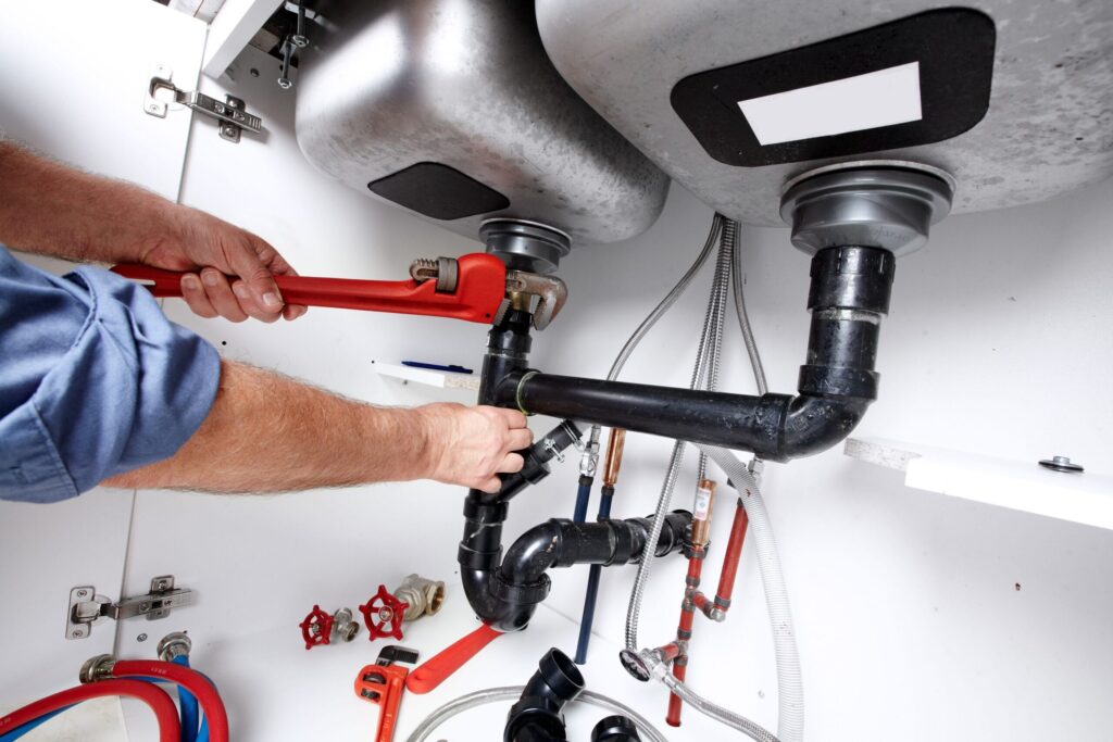 Plumber repairing drain pipes beneath a kitchen sink in Tampa
